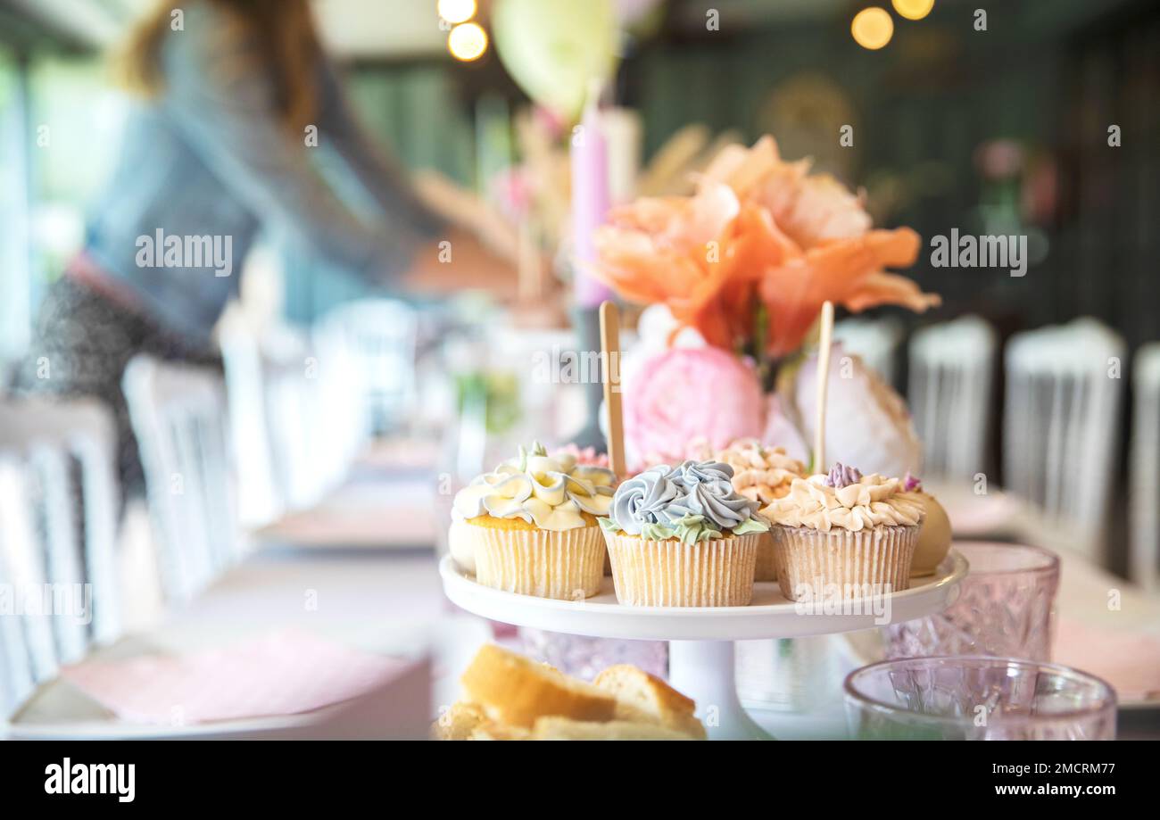 Petits gâteaux frais à la crème fouettée et glaçage aux fleurs démoratives servis sur une assiette sur table de fête, mariage, douche de bébé, thé dînatoire, vacances d'anniversaire Banque D'Images