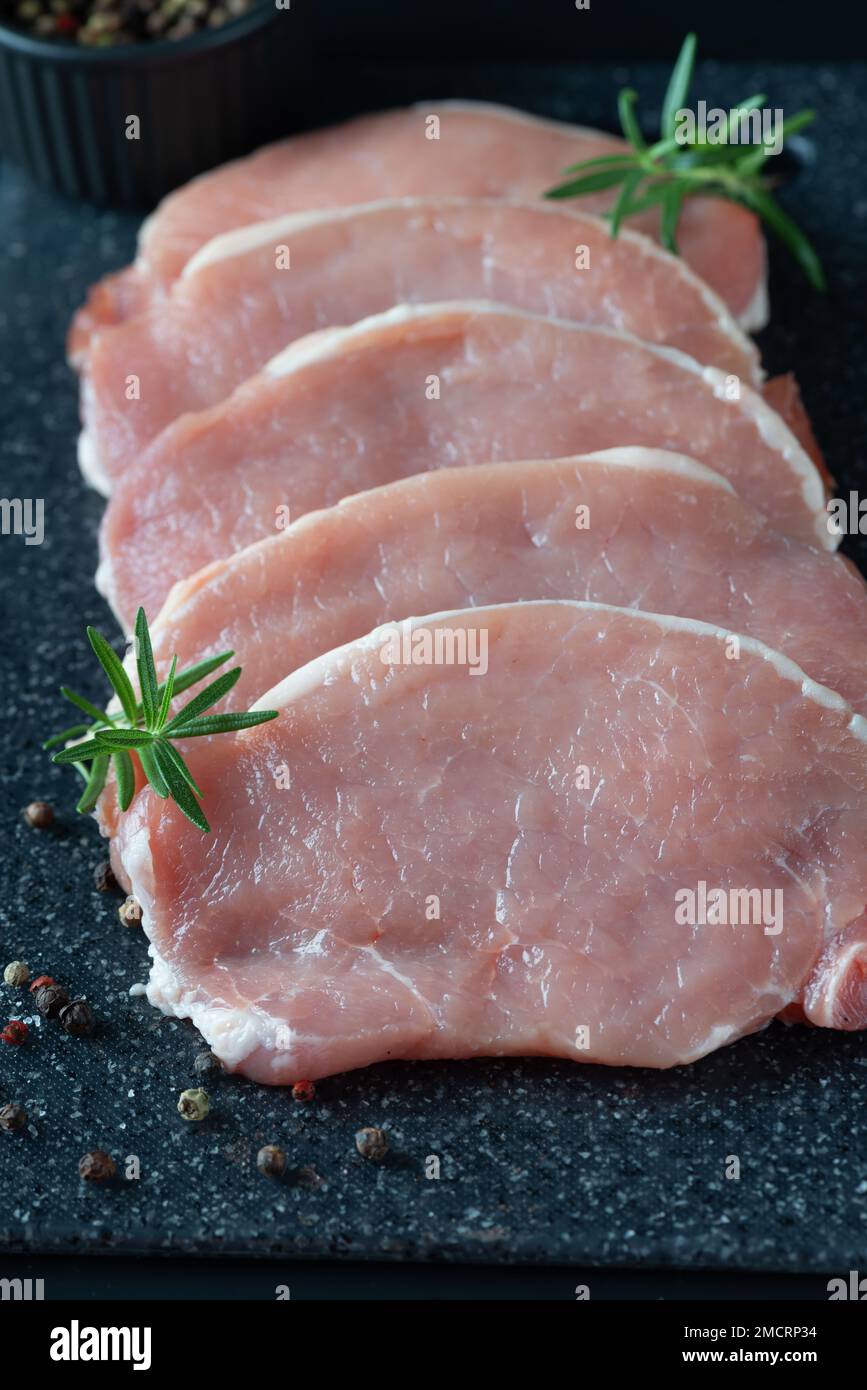 Émincé de viande de porc crue sur une planche à découper foncée Banque D'Images