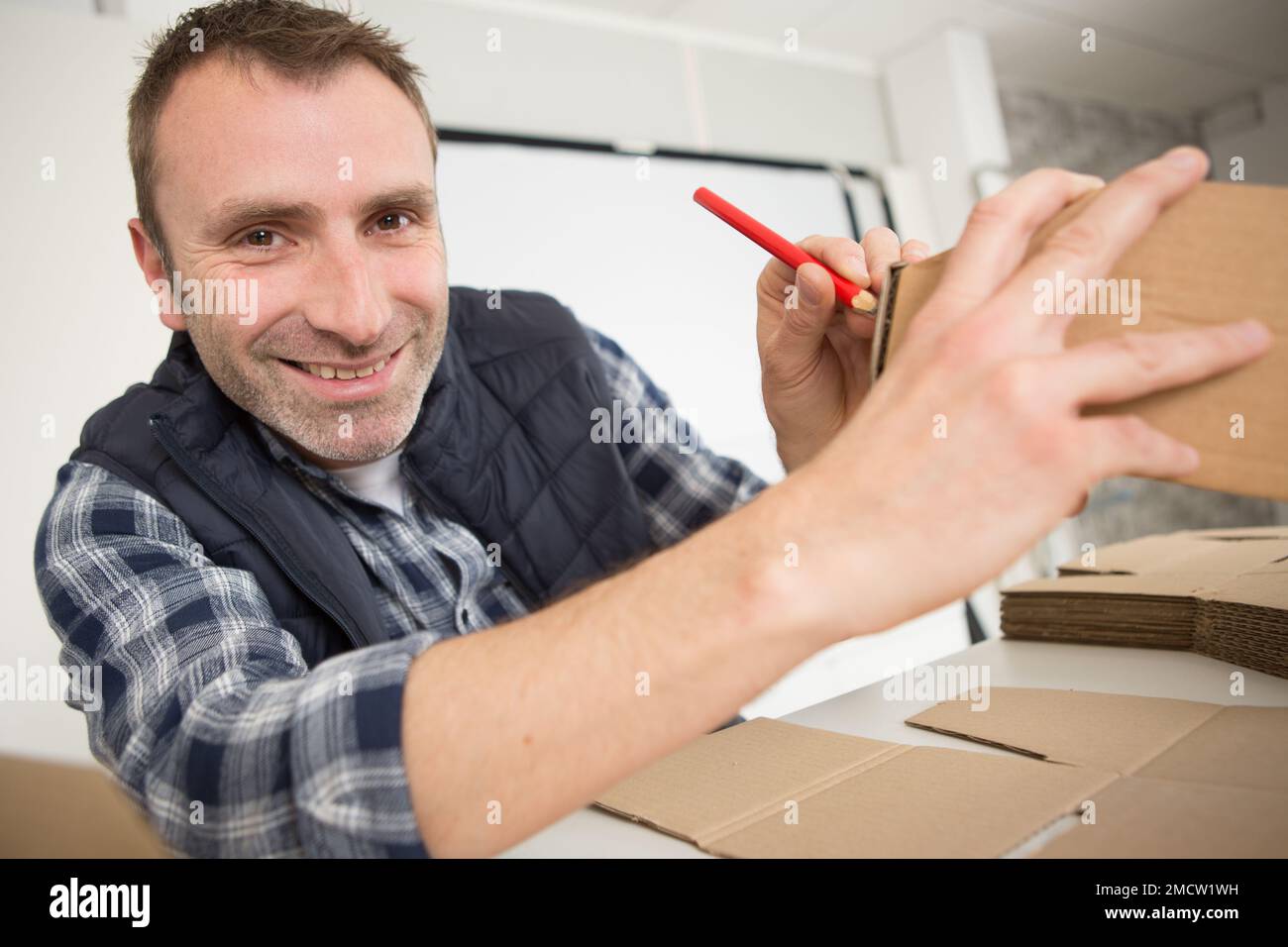 homme plier la boîte à cardans marron et utiliser le stylo pour écrire Banque D'Images