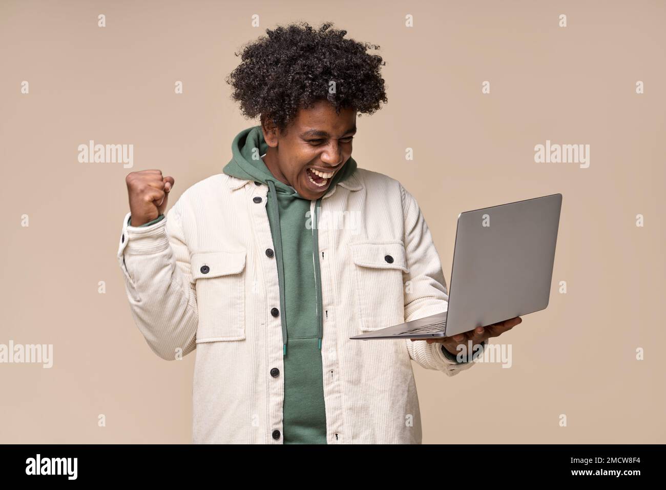 Joyeux adolescent africain gagnant étudiant gars utilisant l'ordinateur portable célébrant la victoire. Banque D'Images