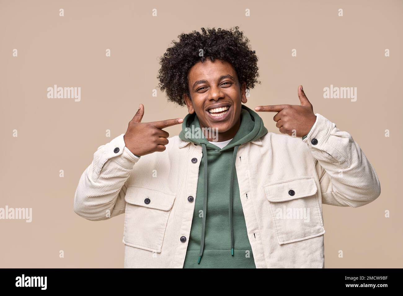 Homme africain souriant pointant vers les dents blanches dentaires faisant de la publicité sur le blanchiment. Banque D'Images
