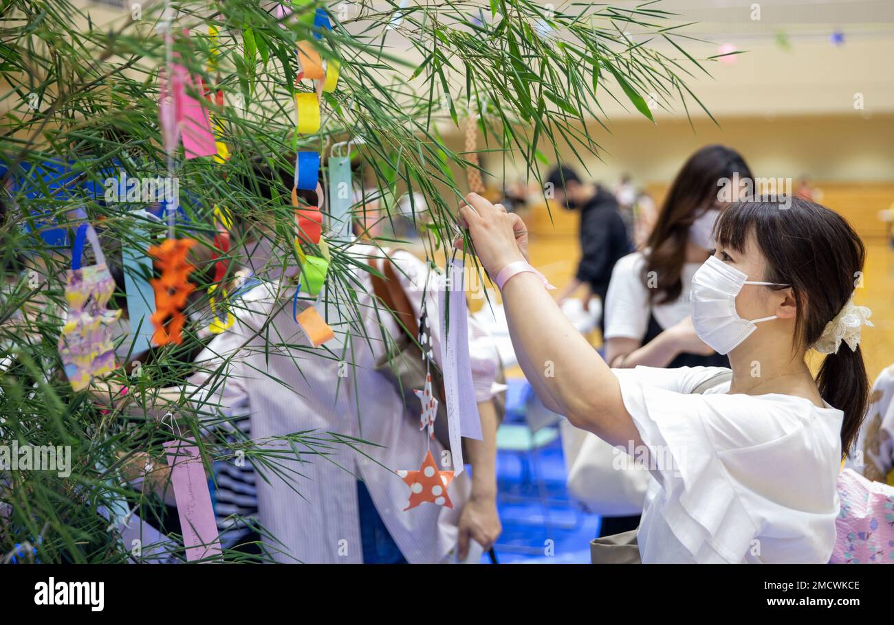 Une femme pend son souhait sur un bambou lors du Festival des étoiles de Tanabata à Iwakuni, Japon, 10 juillet 2022. Le Tanabata Star Festival, originaire de Chine, remonte à des milliers d'années; les gens célèbrent aujourd'hui le festival en accrochant leurs souhaits manuscrits sur des bambous et en accueillant la saison d'été. Ces événements, organisés par la Marine corps Air Station Iwakuni Japanese American Society, ont pour but de présenter aux membres DE SOFA les déguisements, les jeux et les coutumes traditionnels japonais, ce qui renforce encore davantage les liens entre les locaux américains et japonais. Banque D'Images