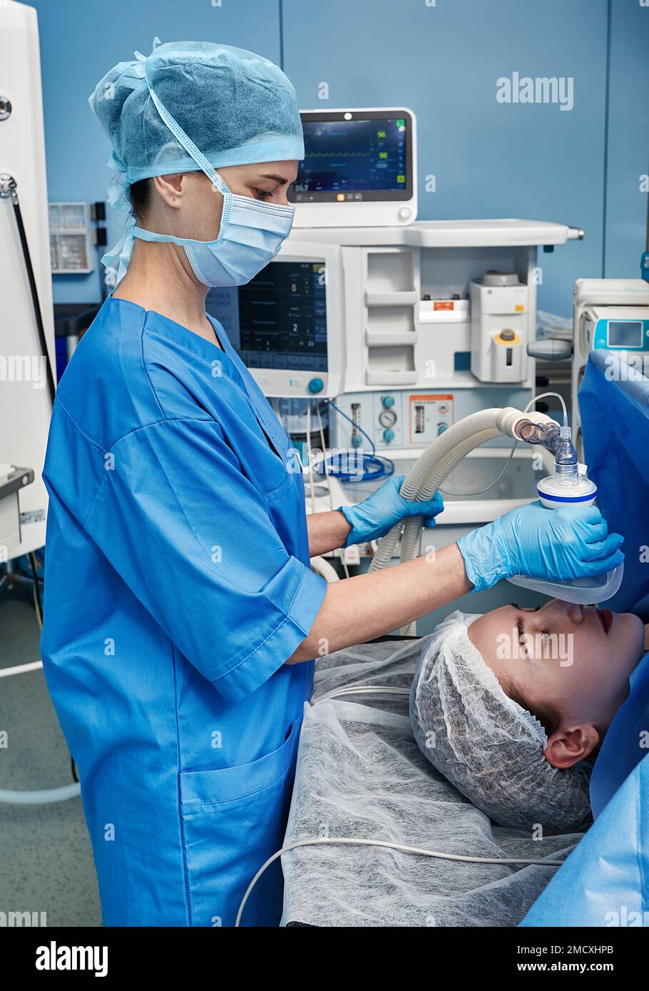 Infirmier chirurgical en gants stériles en plaçant le masque d'anesthésie sur la patiente pendant l'opération chirurgicale dans la salle d'opération de l'hôpital Banque D'Images