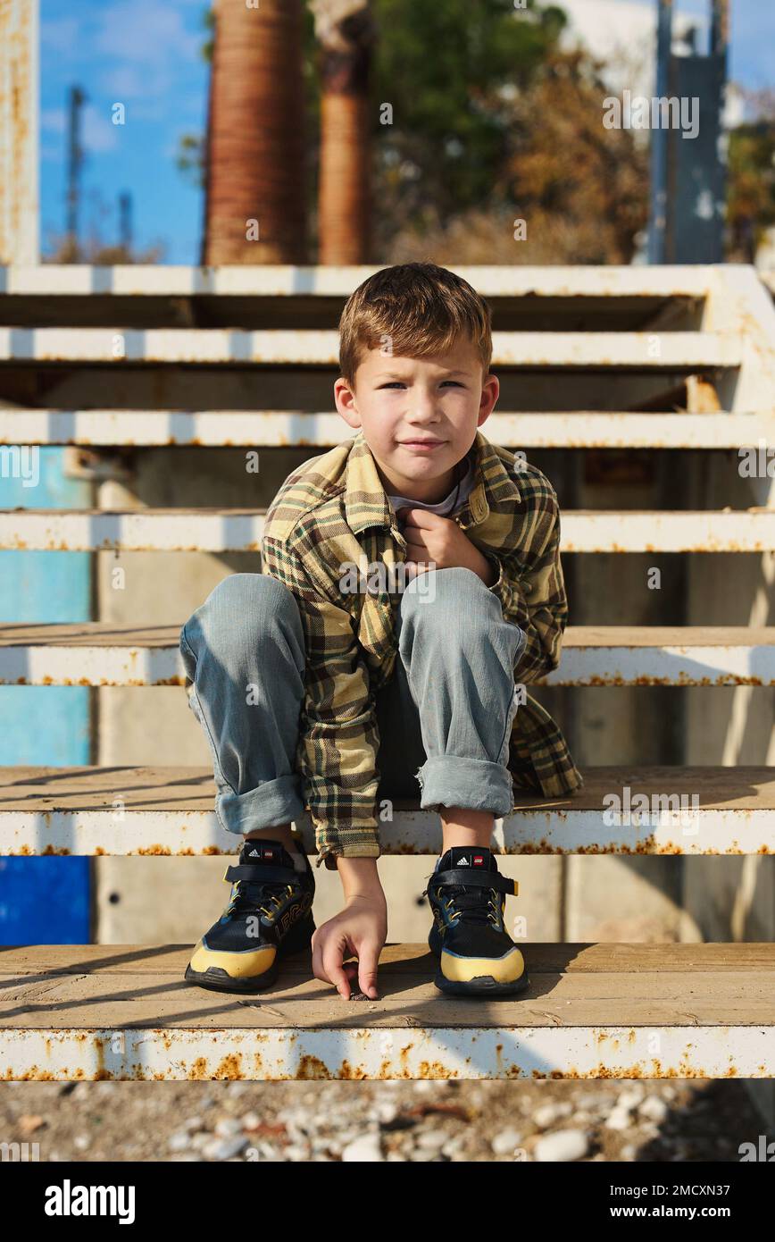 Enfant assis sur les marches. Portrait d un jeune garcon de belle tenue decontractee assis sur les escaliers de la rue. Garcon elegant regardant un appareil photo. Adolescent Photo Stock Alamy