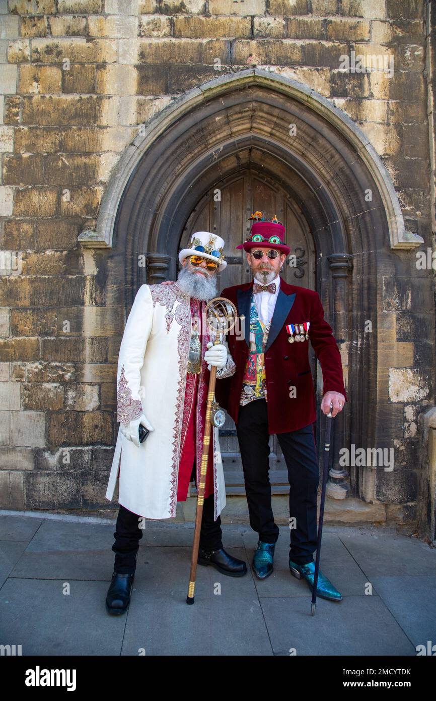 Deux steampunks très habilement habillés debout devant une vieille porte voûtée. Banque D'Images