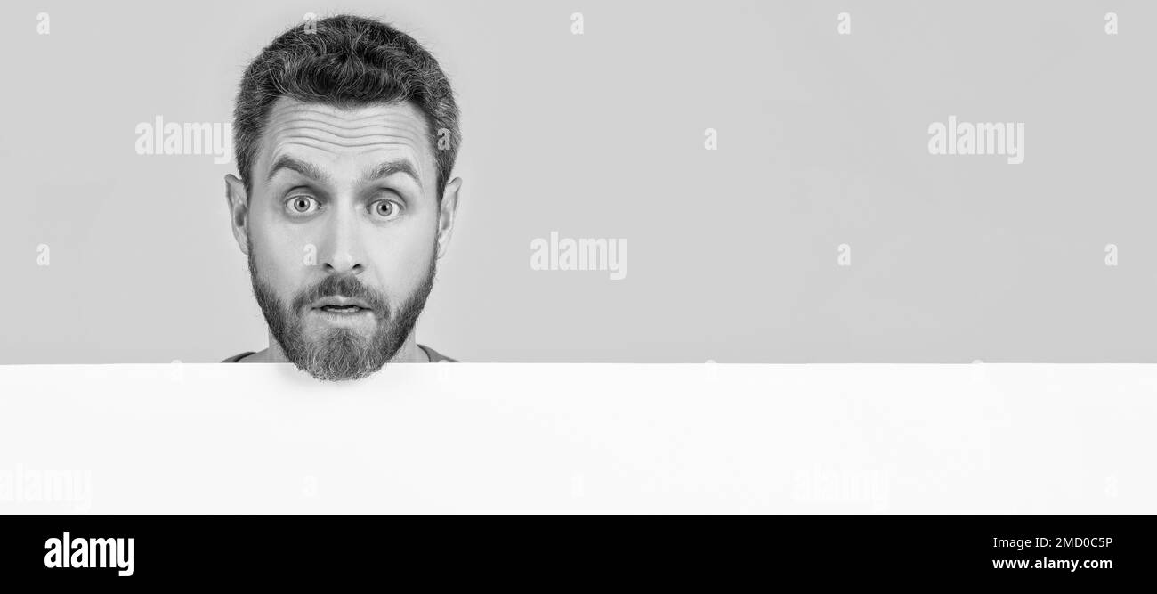 Homme visage portrait, bannière avec espace de copie. Mâle émerveillé derrière le papier noir. Homme surpris avec espace de copie pour la publicité. Banque D'Images