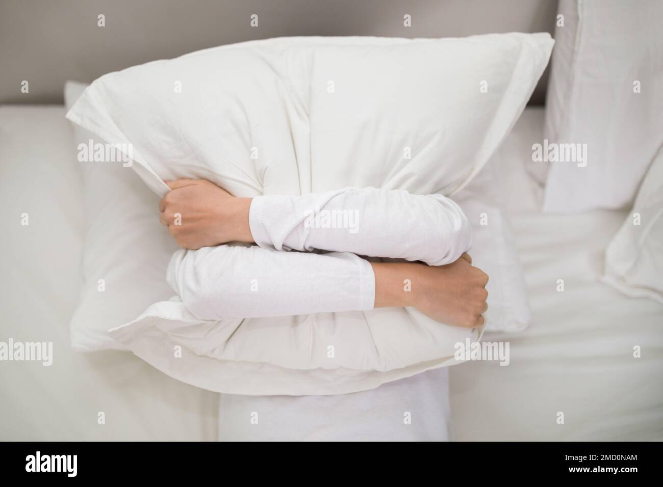 Vue de dessus d'une femme tenant un oreiller blanc sur son visage Banque D'Images