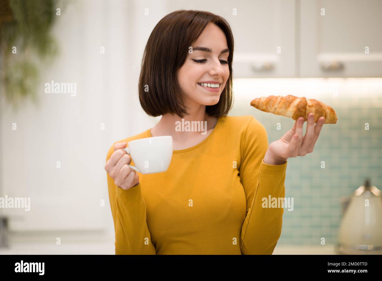 Une jeune femme joyeuse prend le petit déjeuner à la maison Banque D'Images