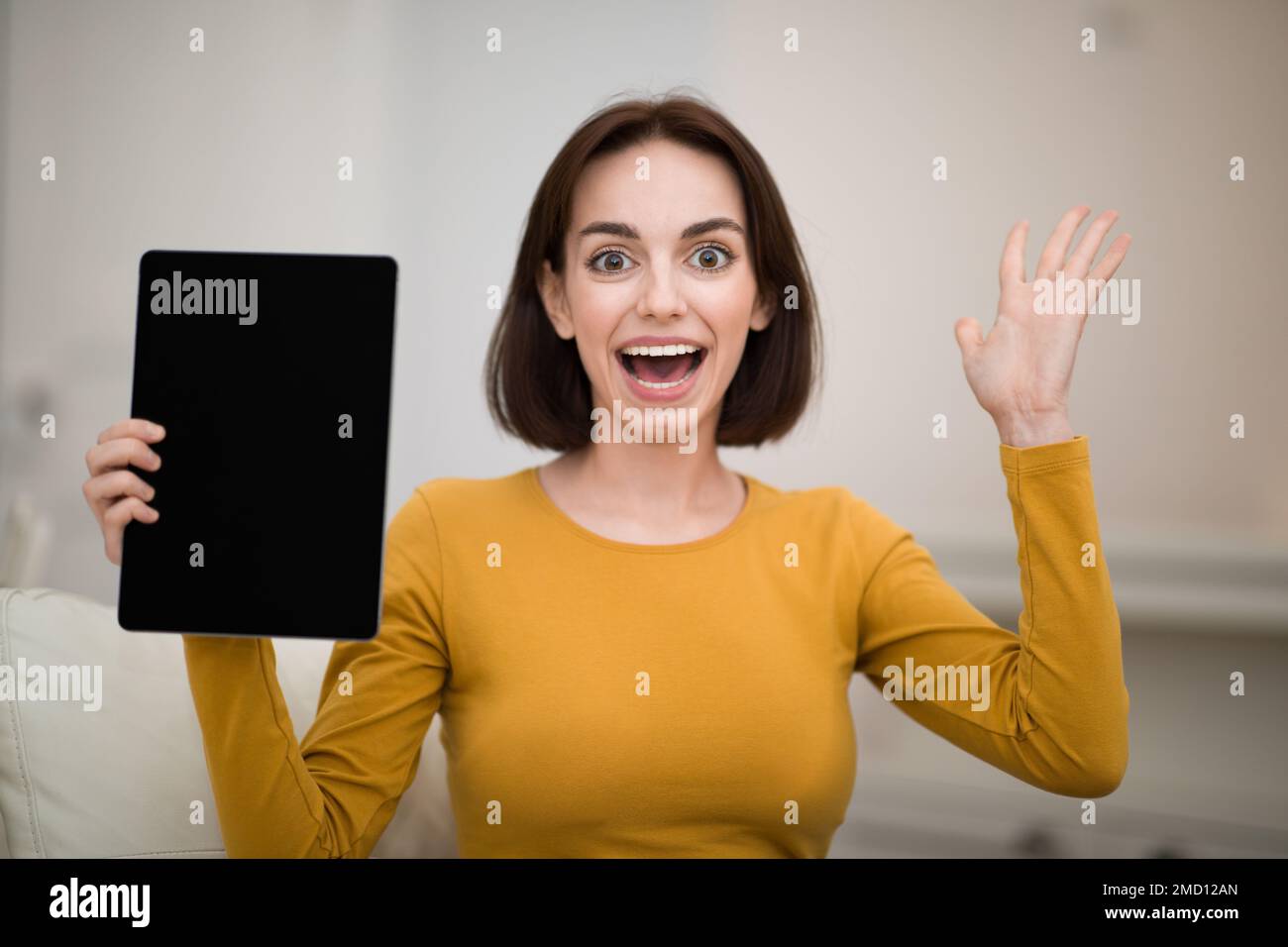 Jeune femme excitée montrant une tablette avec écran noir Banque D'Images