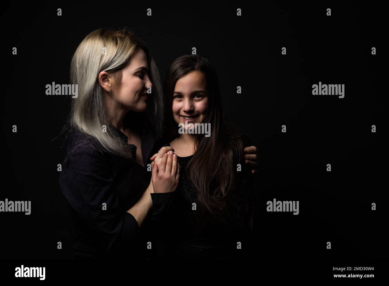 une petite fille avec sa mère prie tout en embrassant Banque D'Images