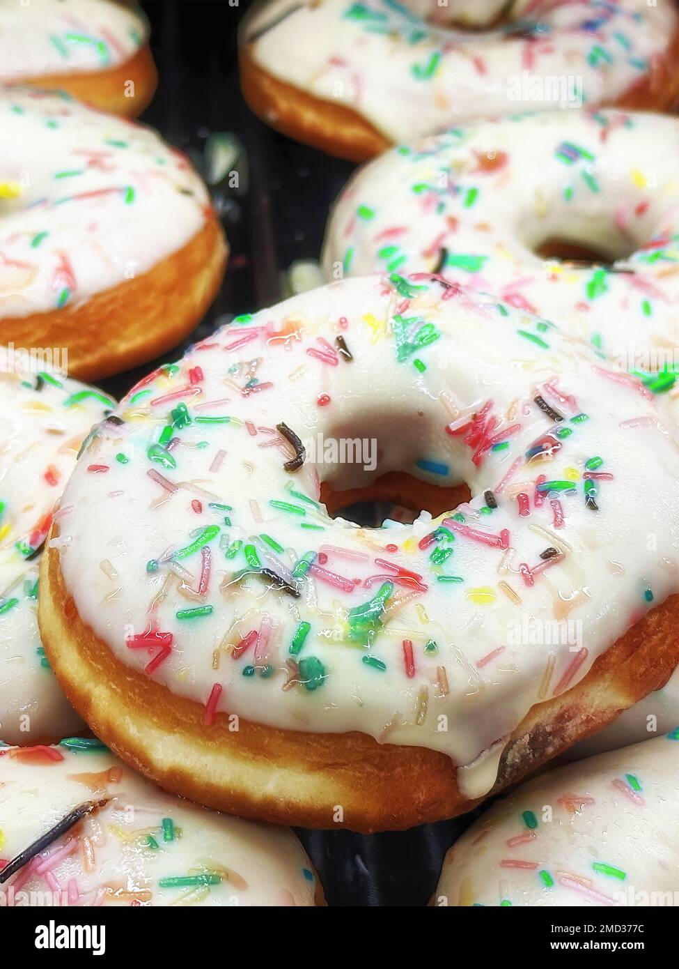 Beignets blancs à glaçage frais et au chocolat sur le marché. Pâtisseries et produits sucrés. Modèle vertical Banque D'Images