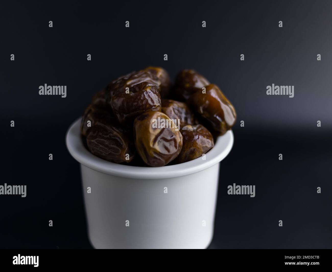 dates isolées sur bol blanc, fond noir Banque D'Images