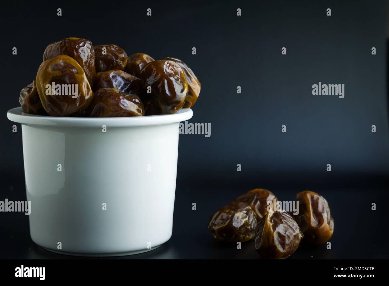 dates isolées sur bol blanc, fond noir Banque D'Images