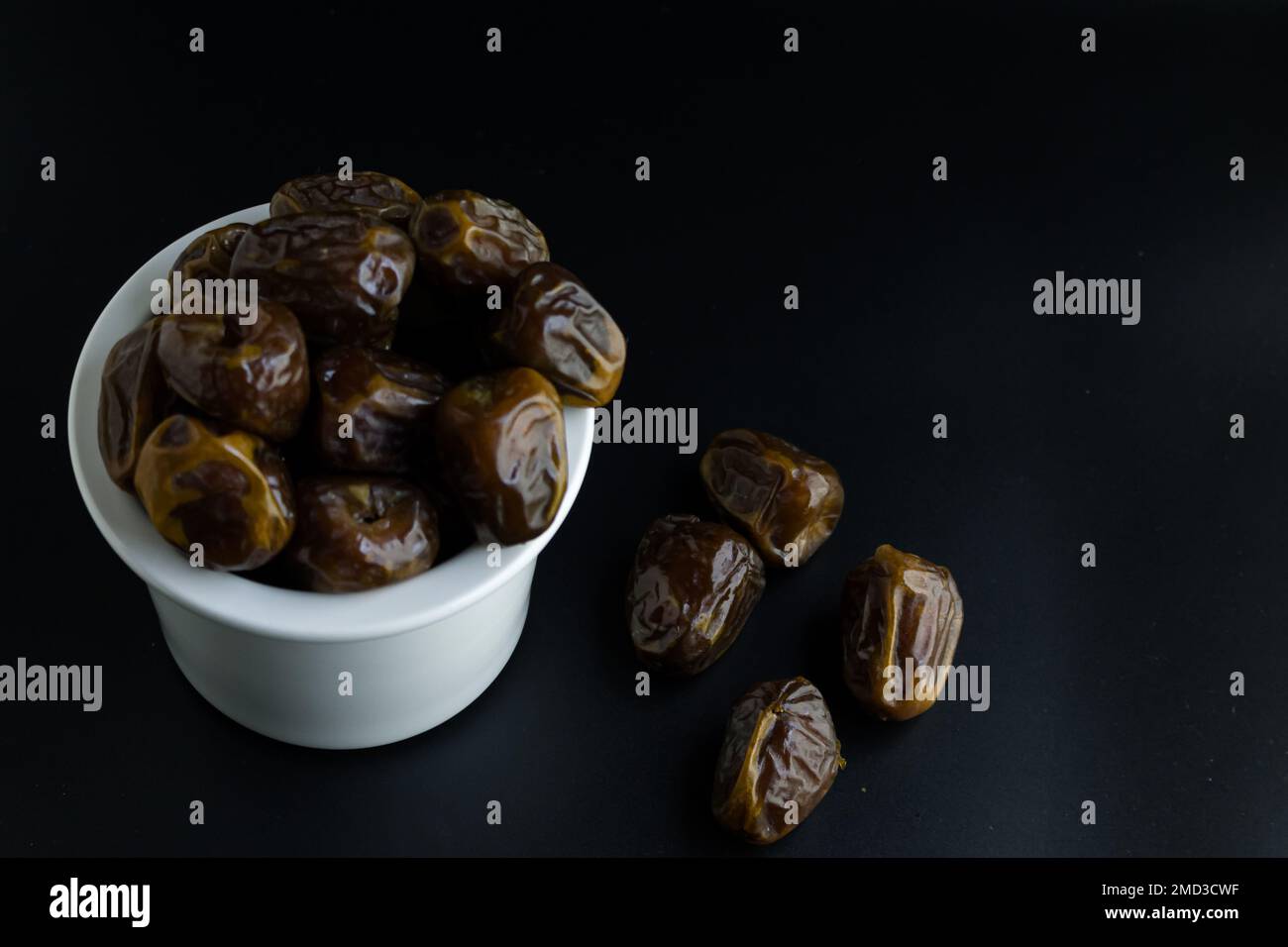 dates isolées sur bol blanc, fond noir Banque D'Images