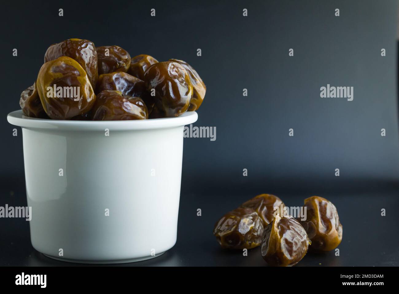 dates isolées sur bol blanc, fond noir Banque D'Images