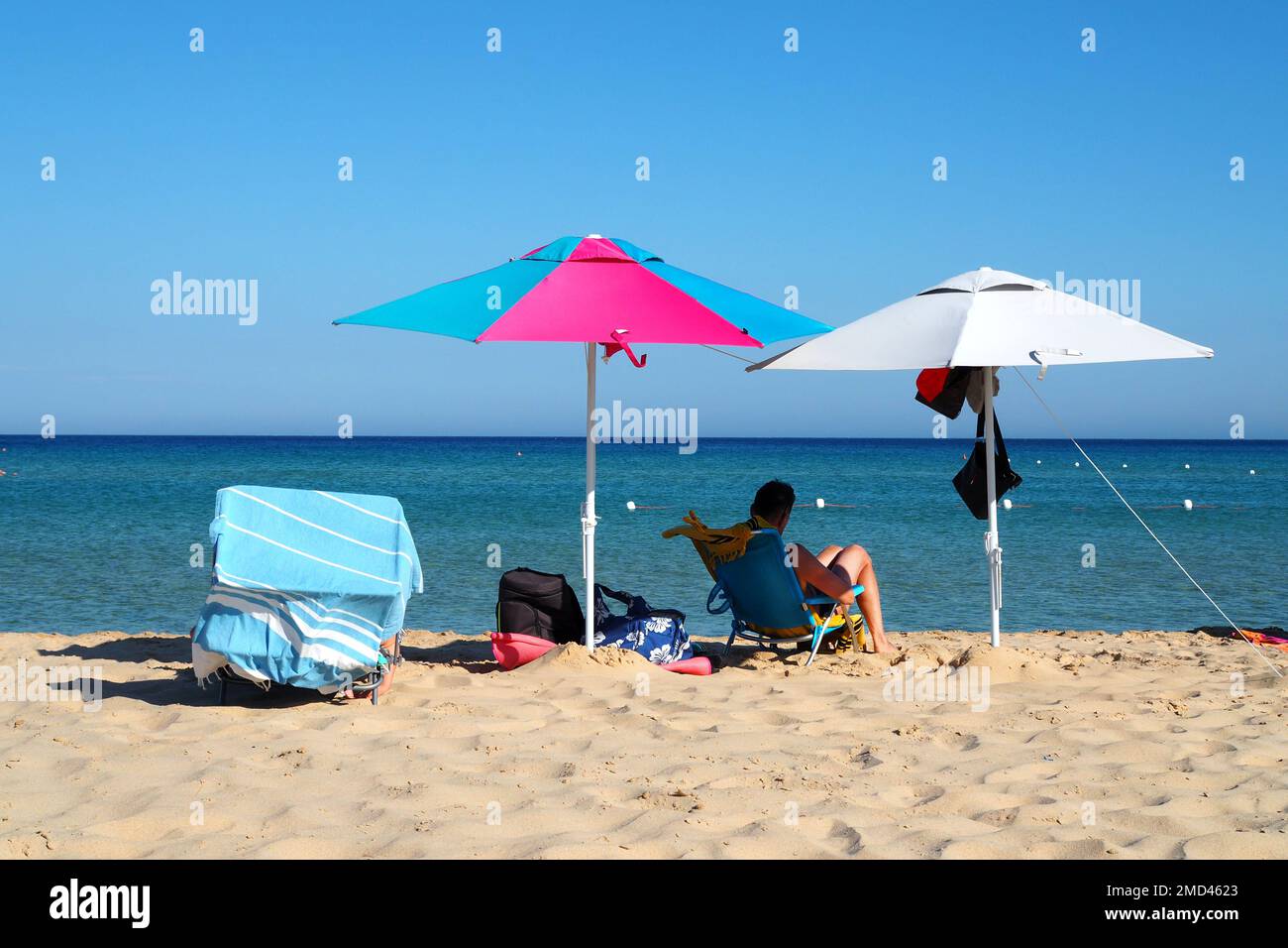 Homme relaxant sous des parasols de plage sur une plage, région de la Sardaigne, Italie Banque D'Images