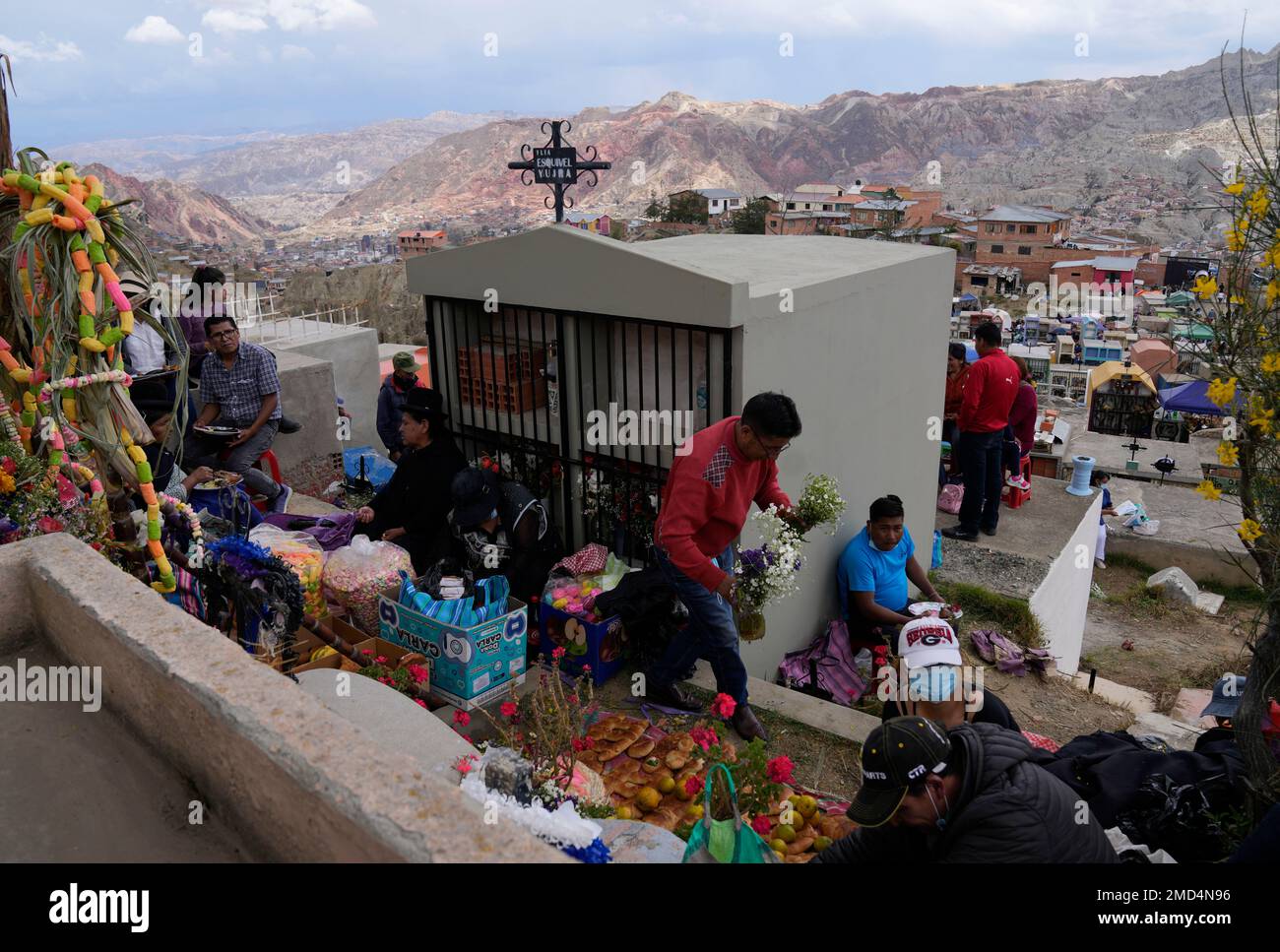 People gather around a tomb covered by offerings of bread and fruit on Day of the Dead at the Bella Vista cemetery in La Paz, Bolivia, Tuesday, Nov. 2, 2021. The Day of the Dead honors the deceased, a tradition which coincides with All Saints Day and All Souls Day celebrated on Nov. 1 and 2. (AP Photo/Juan Karita) Banque D'Images