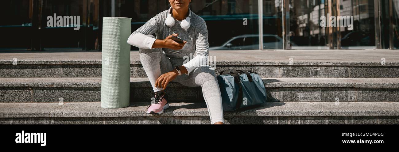 Jeune femme en tenue active regardant la caméra tout en étant assise sur les escaliers Banque D'Images