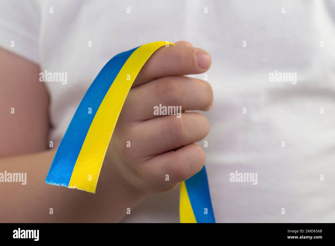 Une fille dans un T-shirt blanc tient un ruban jaune-bleu dans sa main (gros plan). Drapeau d'Etat de l'Ukraine. Symbole national de l'Ukraine. Patriot Banque D'Images