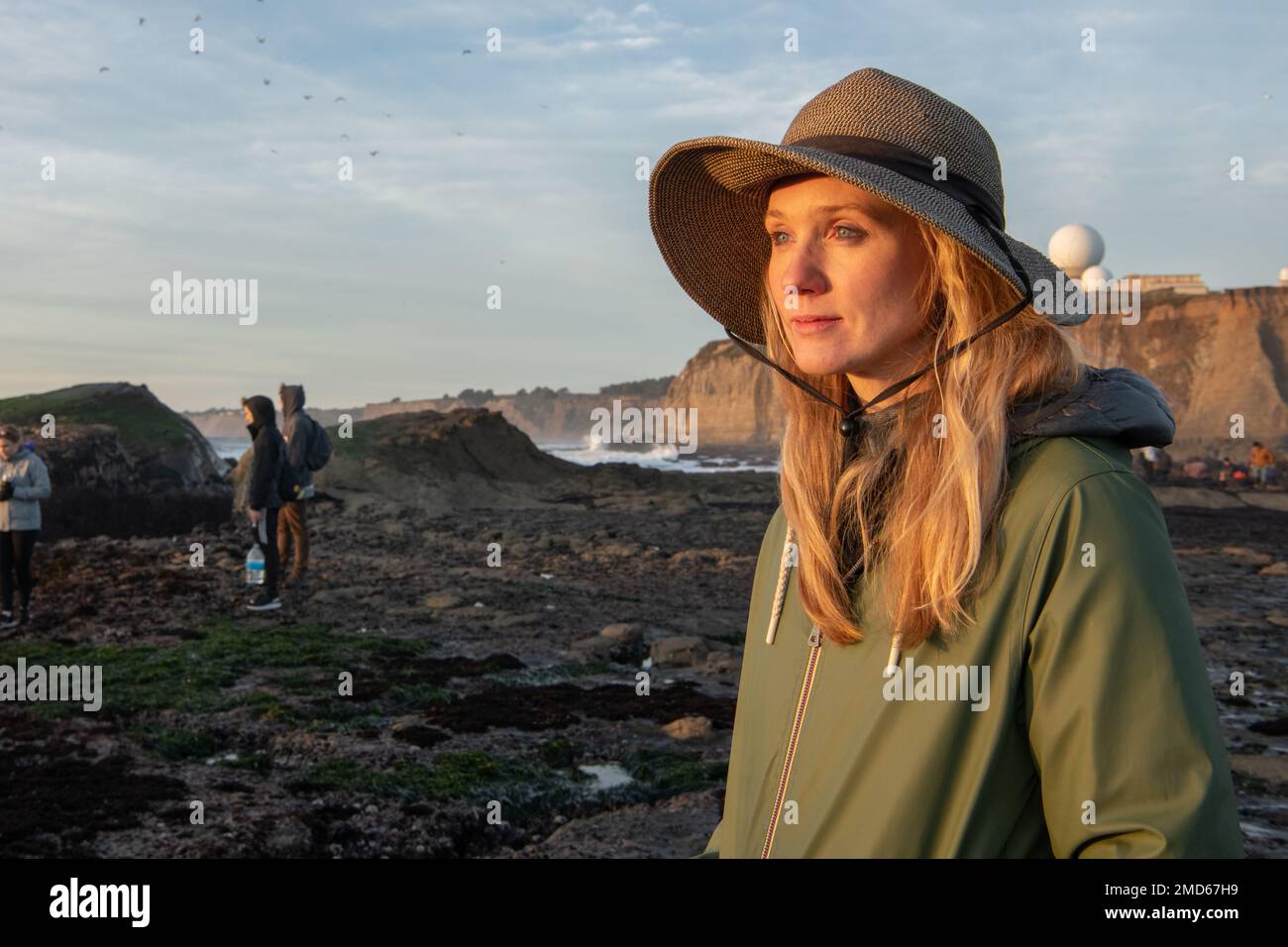 Une femme blonde dans la lumière du soir regardant à la distance à marée basse sur le bord de mer de Californie. Banque D'Images