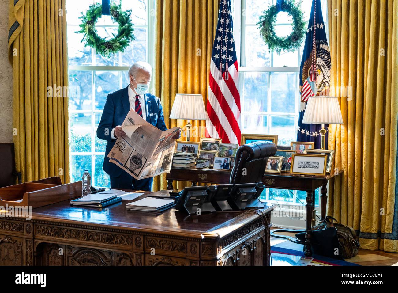 Reportage: Le président Joe Biden lit un journal, jeudi, 23 décembre 2021, dans le bureau ovale de la Maison Blanche Banque D'Images