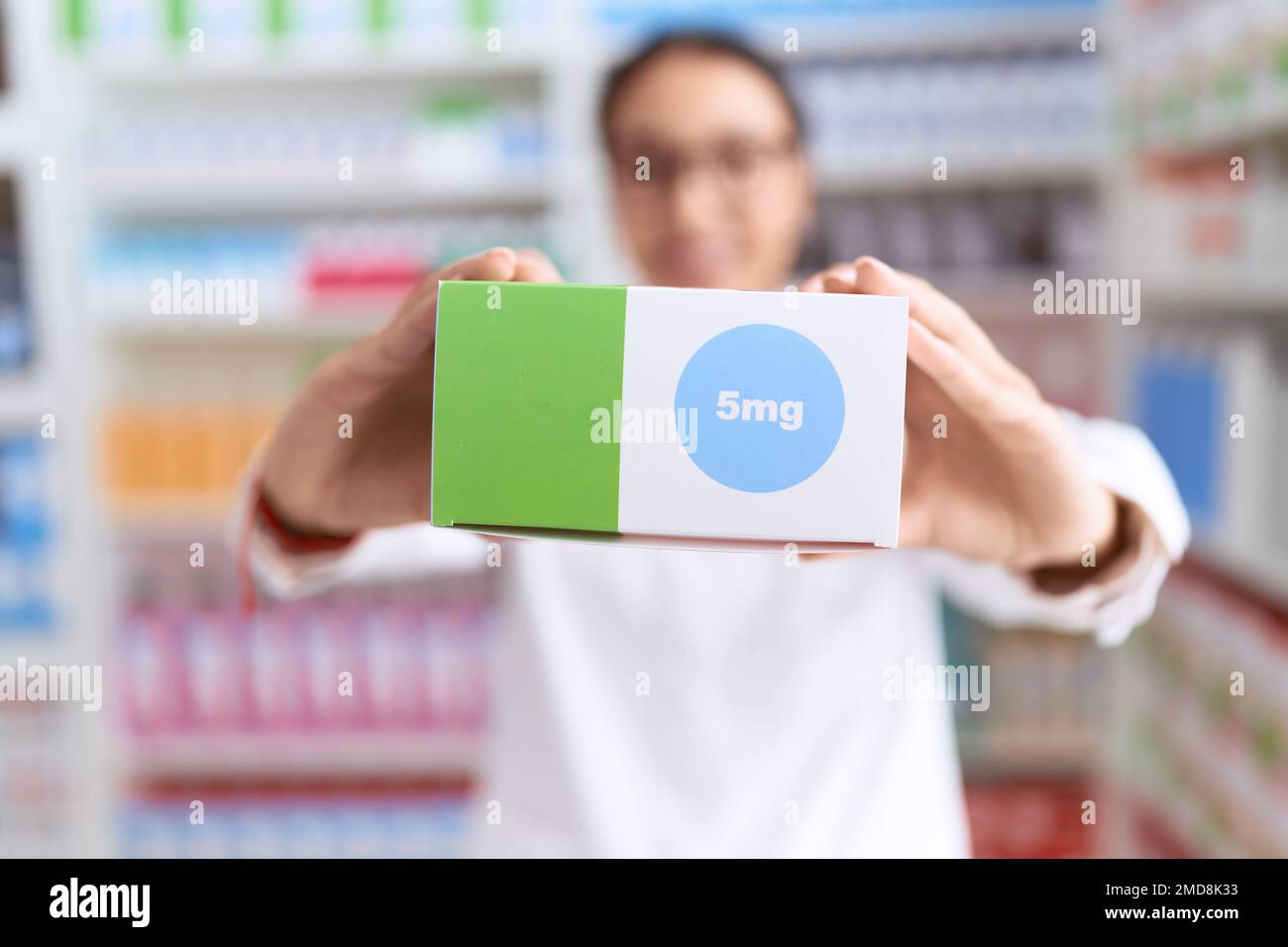 Jeune femme arabe pharmacien souriant confiante en tenant le paquet de médicaments dans la rue Banque D'Images