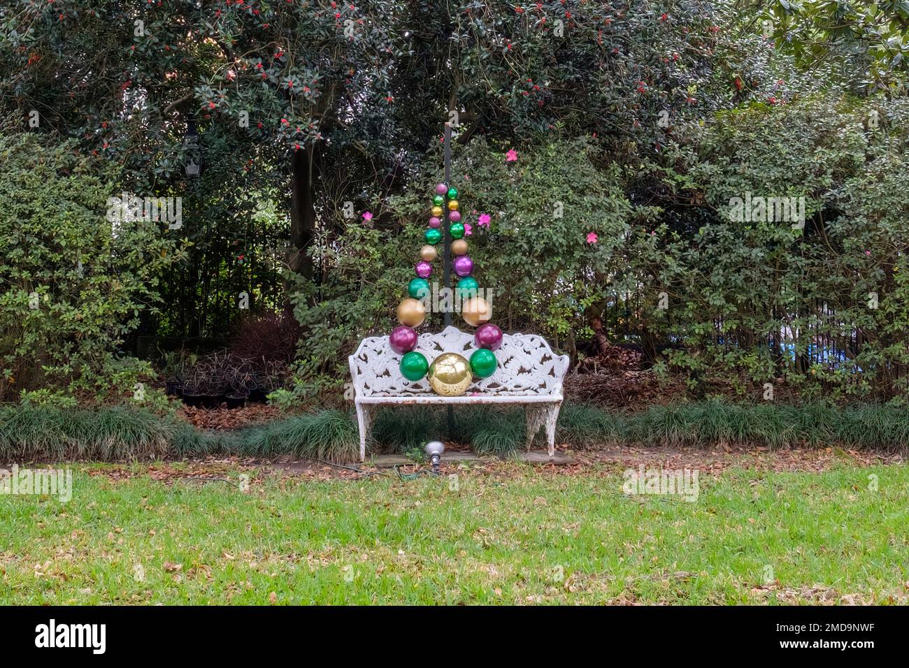 Des perles géantes de Mardi gras drapées sur un banc blanc orné dans un jardin résidentiel Banque D'Images