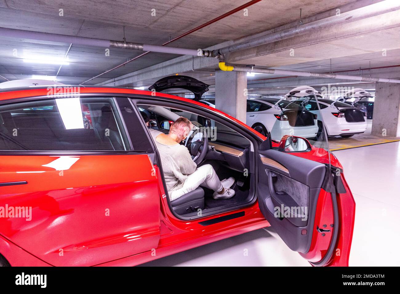 Tesla modèle 3, femme dans le siège conducteur de son nouveau modèle 3 recueilli de Tesla à Sydney, Australie parking sécurisé.modèle et propriété libérés Banque D'Images