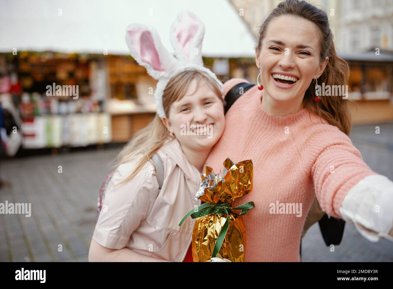 Pâques amusant. bonne mère moderne et fille adolescente avec oeuf de pâques doré à la foire dans la ville. Banque D'Images
