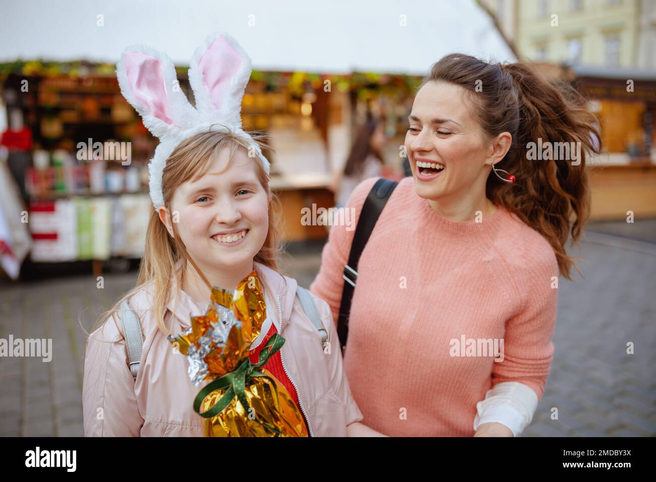 Pâques amusant. une jeune mère souriante et une fille adolescente avec un œuf de pâques doré à la foire de la ville. Banque D'Images