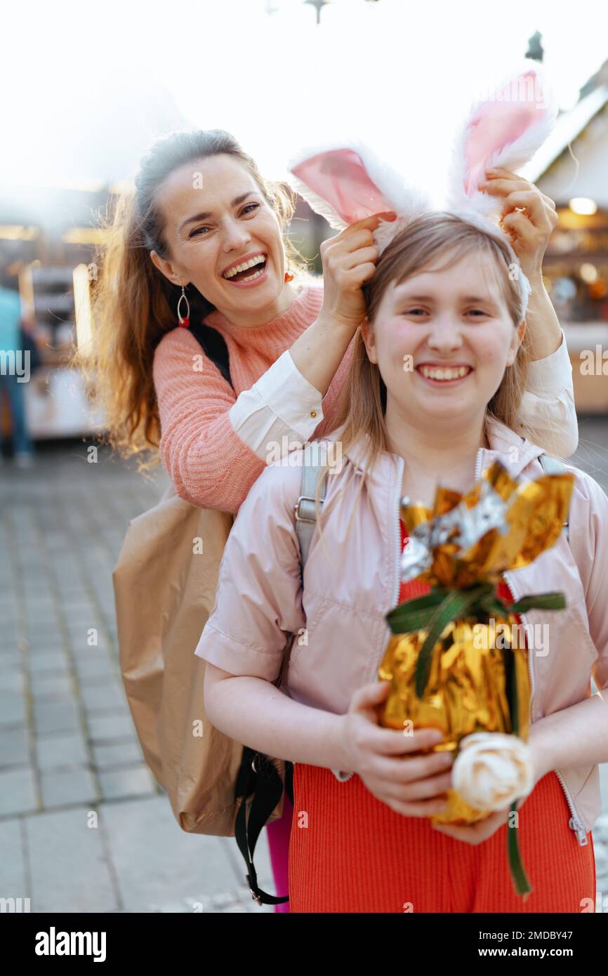 Pâques amusant. Portrait de la mère et de l'enfant modernes souriants avec l'oeuf de pâques doré à la foire dans la ville. Banque D'Images