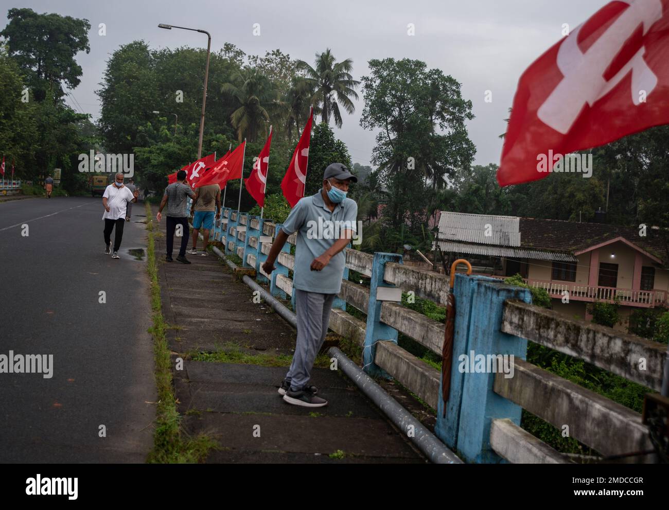 A man wearing mask as a precaution against the coronavirus performs morning exercises on a bridge where Communist party flags are displayed in Kochi, Kerala state, India, Wednesday, Oct.6, 2021. (AP Photo/R S Iyer) Banque D'Images