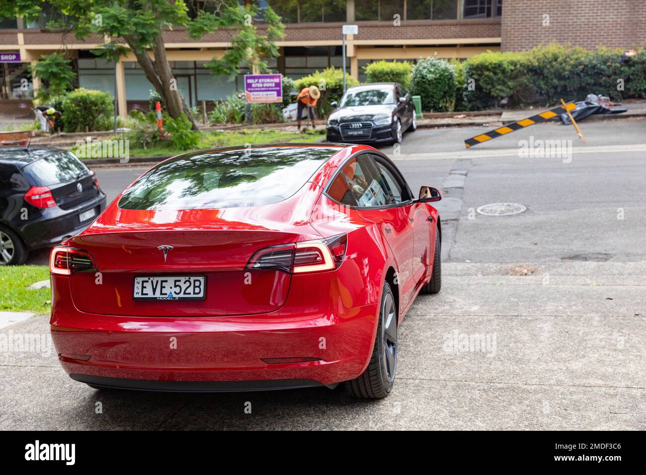 Red Tesla modèle 3 , nouvelle voiture en cours de conduite depuis le centre de remise de la collection Tesla à Chatswood, Sydney, Nouvelle-Galles du Sud, Australie Banque D'Images
