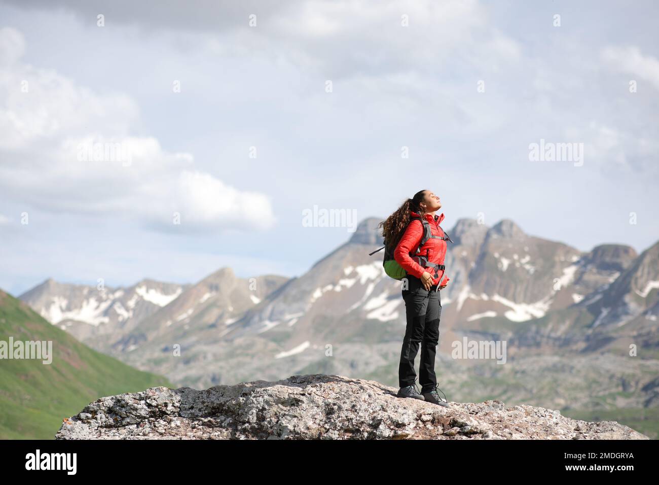 Randonneur en rouge respirant de l'air frais au sommet d'une montagne Banque D'Images