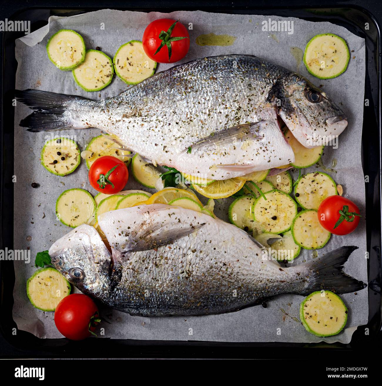 Poisson dorado cru avec des ingrédients pour faire sur une plaque de cuisson. Vue de dessus Banque D'Images