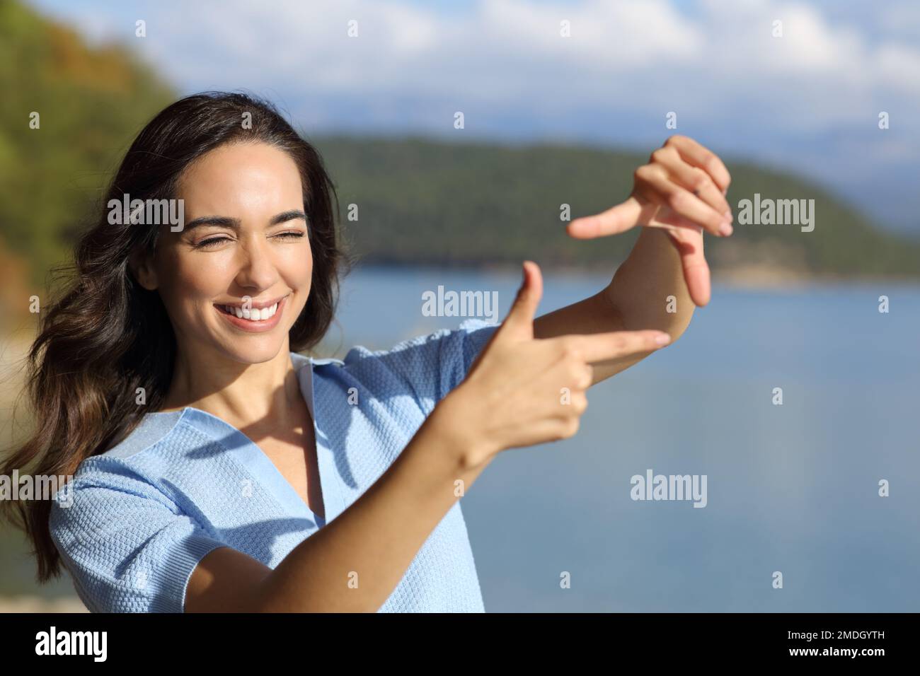 Bonne femme cadrage avec les mains calculant la perspective dans un lac de montagne Banque D'Images