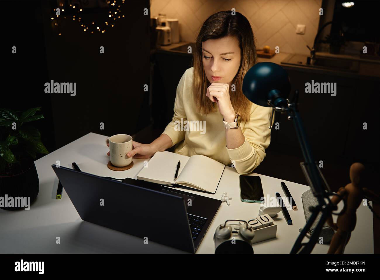 Femme concentrée dans des vêtements décontractés regardant l'écran d'ordinateur portable et dessin illustration dans le bloc-notes. Une femme indépendante travaille dans un bureau à domicile. Au-dessus Banque D'Images