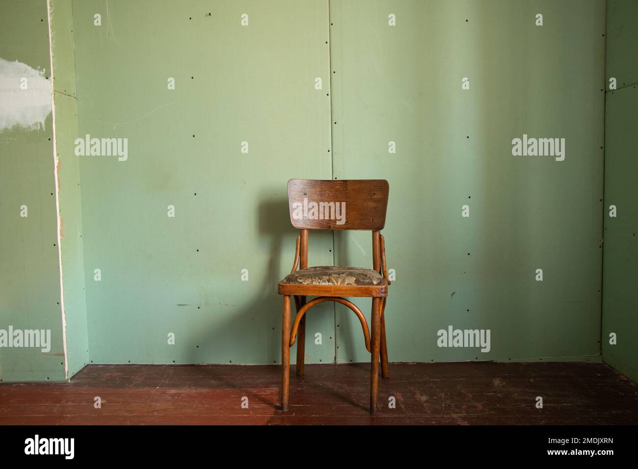 un vieux fauteuil en bois se tient dans une pièce vide sur le sol recouvert de placoplâtre, chambre vide et pauvreté, chaise Banque D'Images