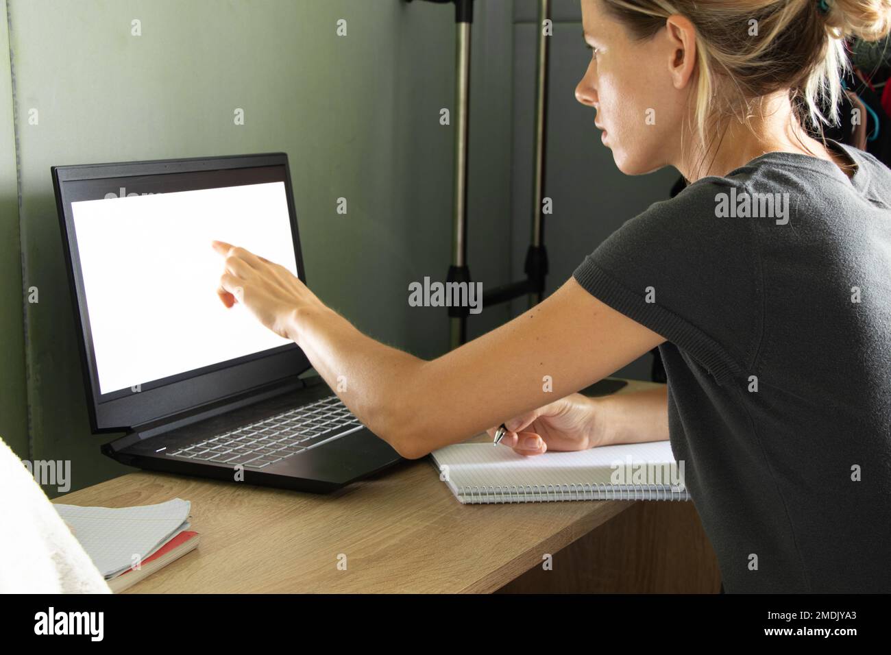 une fille s'assoit à une table et regarde un ordinateur portable avec un mauvais écran à la maison, travaillant sur l'auto-isolation à la maison, un ordinateur portable avec un mauvais écran Banque D'Images