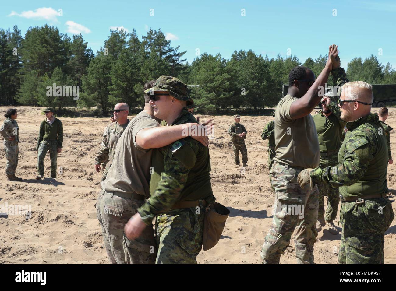 ÉTATS-UNIS Soldats affectés à Alpha Battery, 3rd Bataillon, 29th Régiment d'artillerie de campagne, 3rd équipe de combat de la brigade blindée, 4th Division d'infanterie, et les soldats canadiens de l'OTAN en présence avancée se secouent la main après un tir de compétition de guerre dans les champs du site d'opération avancée Adazi, Lettonie, 25 juillet 2022. L'ABCT de 3/4 est parmi les autres unités assignées à la Division d'infanterie de 1st, travaillant fièrement aux côtés des alliés de l'OTAN et des partenaires de sécurité régionaux pour fournir des forces crédibles au combat au V corps, le corps déployé avancé de l'Amérique en Europe. Banque D'Images