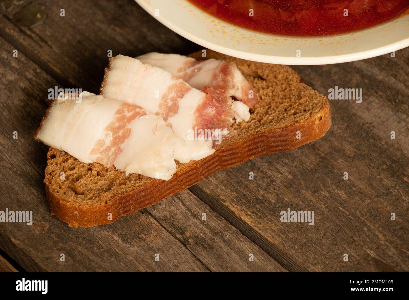 Une assiette de borscht ukrainien traditionnel et un morceau de pain avec du bacon sur une table en bois, déjeuner Banque D'Images Une assiette de borscht ukrainien traditionnel et un morceau de pain avec du bacon sur une table en bois, déjeuner Banque D'Images