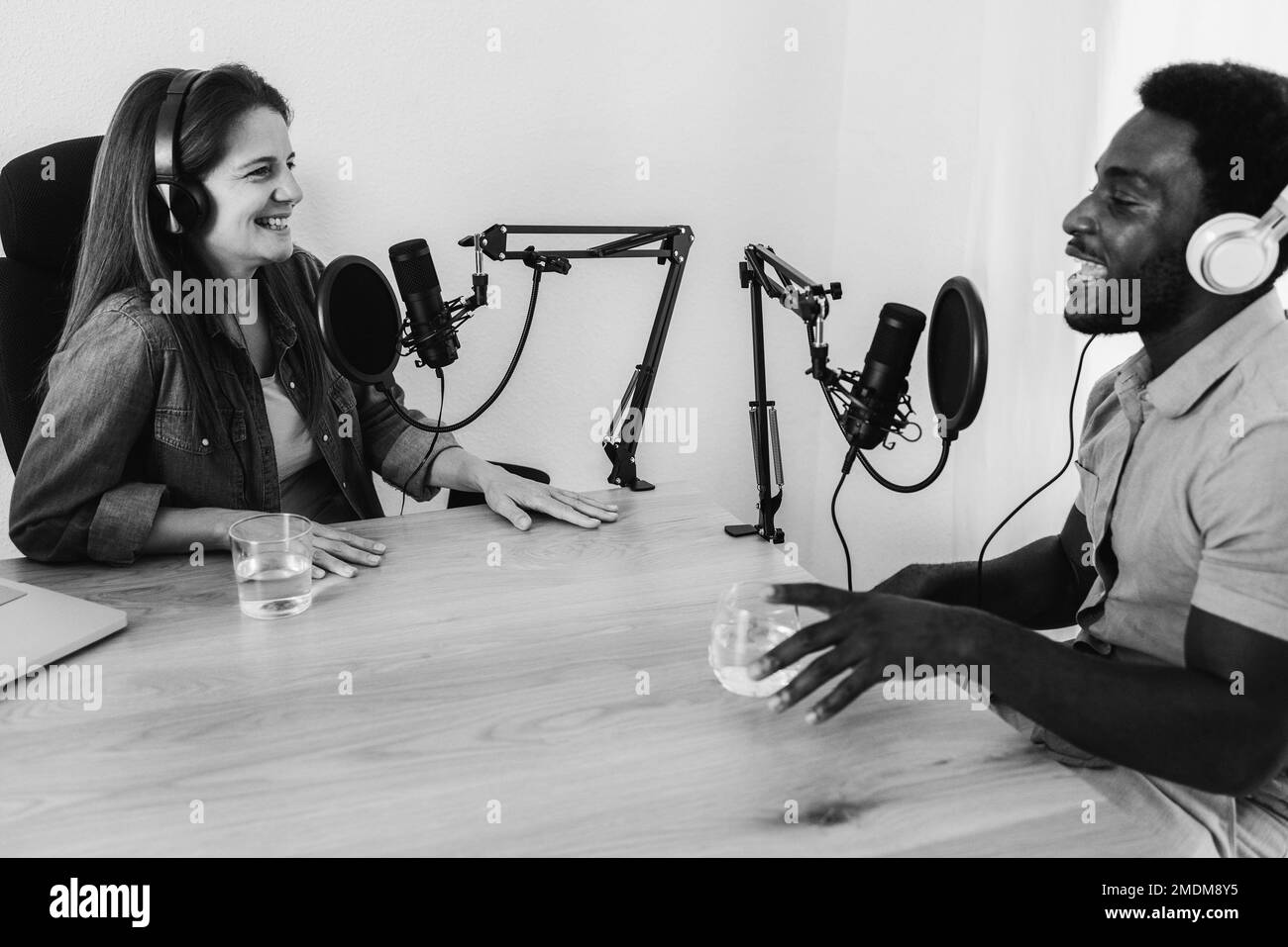 Le podcast en streaming est diffusé en mode multiracial dans un studio numérique - mise au point principale sur le microphone gauche - montage en noir et blanc Banque D'Images