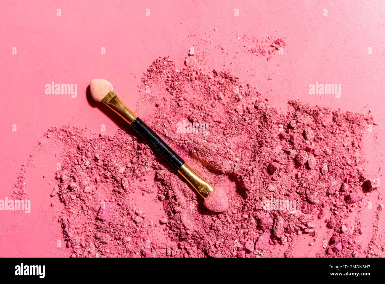 Ombres à paupières roses écrasées avec pinceau ou outil de mélange d'applicateur sur fond rose Banque D'Images