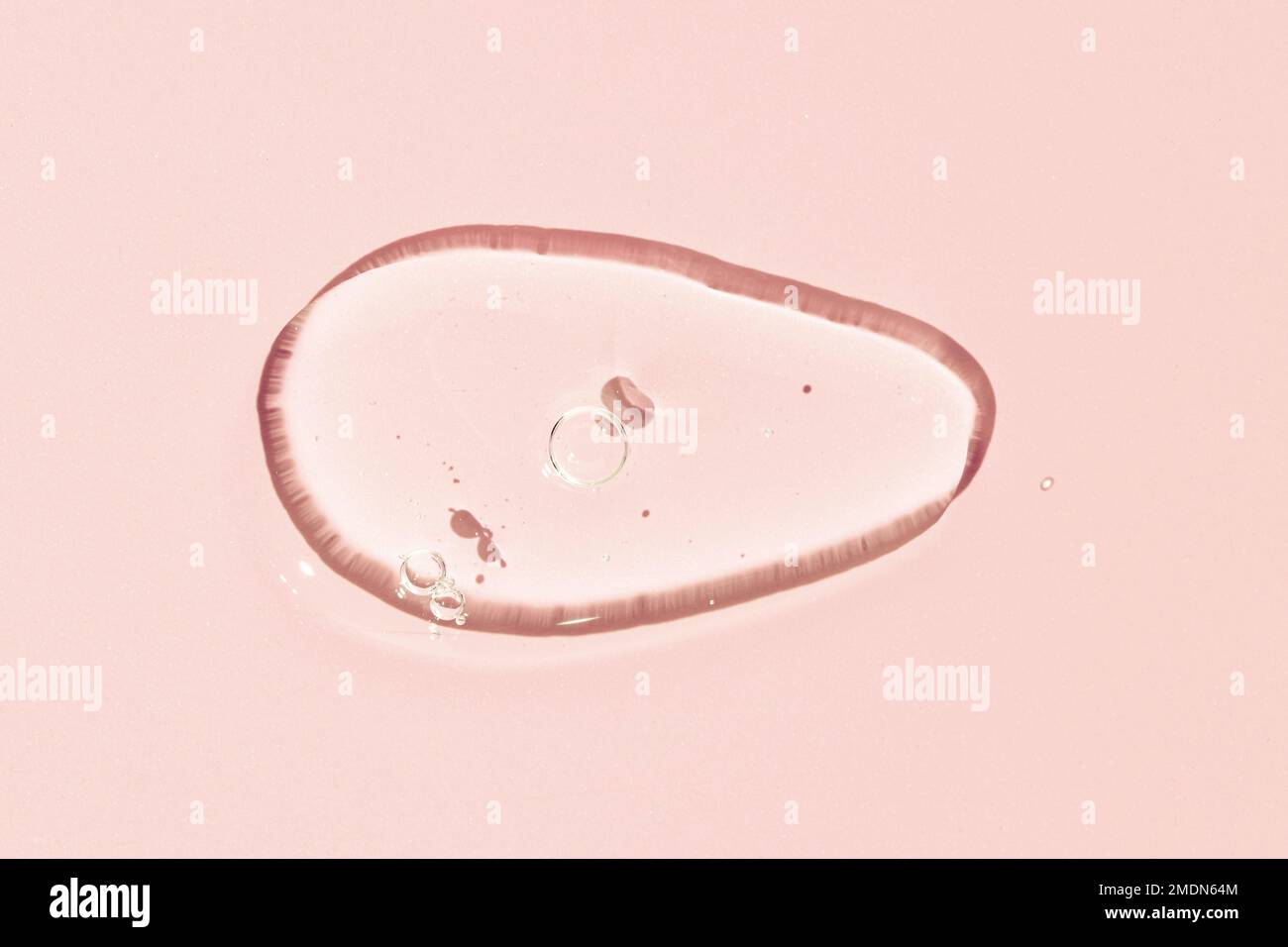 Gel liquide transparent texture à taches cosmétiques. Gel liquide transparent avec bulles isolées sur fond rose Banque D'Images