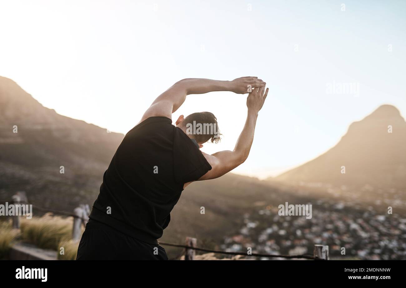 Gardez ces muscles au chaud et éveillés. Vue arrière d'un jeune sportif qui fait de l'exercice en plein air. Banque D'Images
