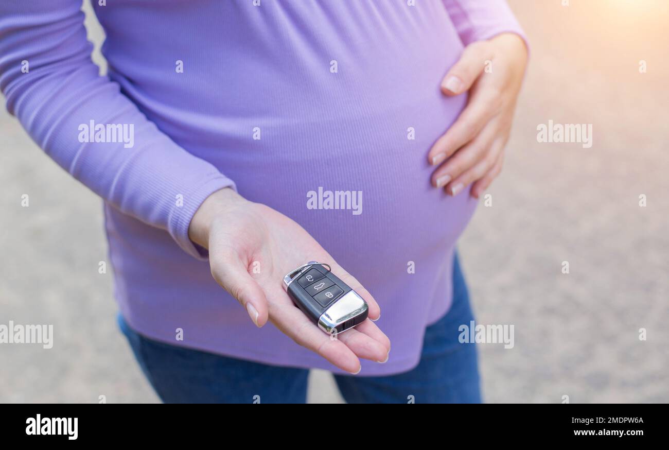 Une fille enceinte avec un gros ventre tient une clé de voiture dans sa  main. Connu pour les dangers de conduire une voiture pendant la grossesse,  la menace de fausse couche. TRAV