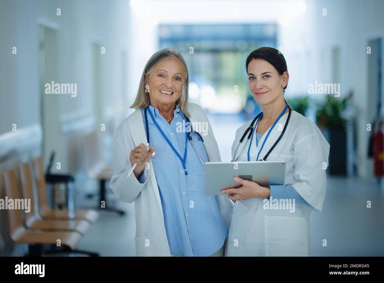 Femme plus âgée médecin donnant des conseils à son jeune collègue, discutant dans le couloir de l'hôpital. Concept de soins de santé. Banque D'Images