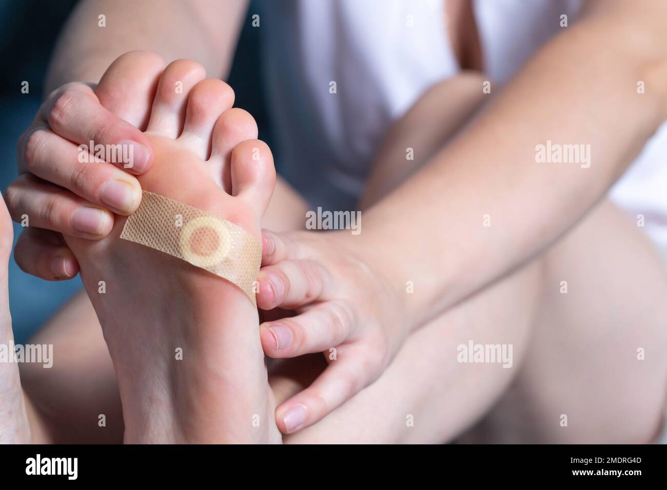 Une fille colle un plâtre médical pour verrues plantaires sur sa jambe. Traitement de callus Banque D'Images