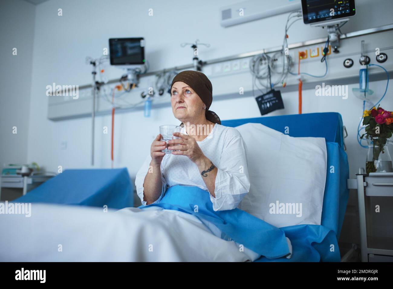 Femme âgée assise dans la chambre d'hôpital après une chimiothérapie. Banque D'Images