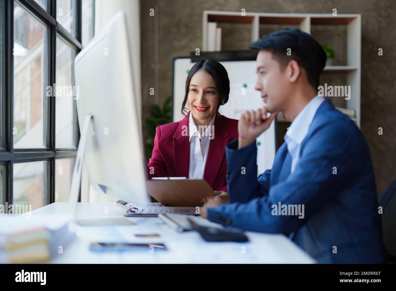 Belle femme d'affaires consultant parlant avec un homme d'affaires asiatique dans la salle de réunion avec le nouveau marché financier. Concept comptable Banque D'Images